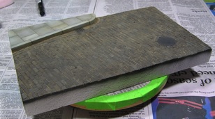 Painted and weathered with oil washes, Mig pigments, and graphite powder on manhole cover.